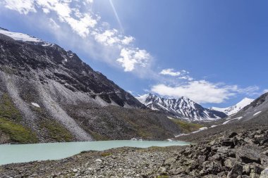 Mavi nehir manzarası ve Tien Shan dağlarının karlı tepeleri baharda güneşli bir günde. 