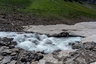 Güneşli baharda kayalık dağlarda akan hızlı dağ deresinin resimsel görüntüsü 
