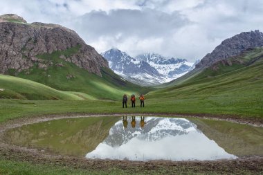 Kırgızistan Yazı. Bir grup turist sırt çantalarıyla yamaçlarda dağ yürüyüşüne çıktılar..