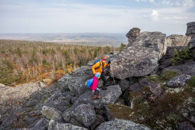 Babası kızıyla birlikte dağlarda kayalıklarda, kayalara tırmanıyor, ailesiyle, babasıyla dinleniyor. Açık havada.
