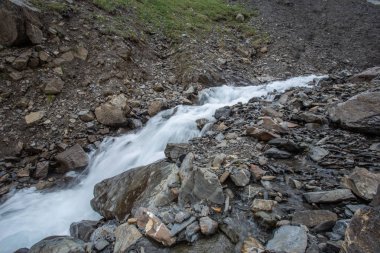 Güneşli baharda kayalık dağlarda akan hızlı dağ deresinin resimsel görüntüsü 