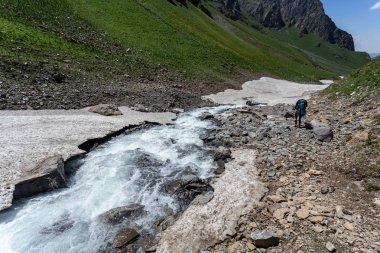 Güneşli kış günlerinde, sırt çantalı, karlı dağlarda yürüyüş yapan sıcak spor elbiseli bir gezgin. 