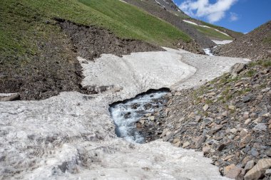 Güneşli baharda kayalık dağlarda akan hızlı dağ nehrinin resimsel manzarası 