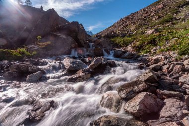 Güneşli baharda kayalık dağlarda akan hızlı dağ deresinin resimsel görüntüsü 