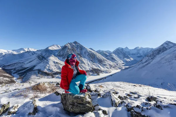 traveler in warm sporty clothes hiking in snowy mountains at sunny winter day