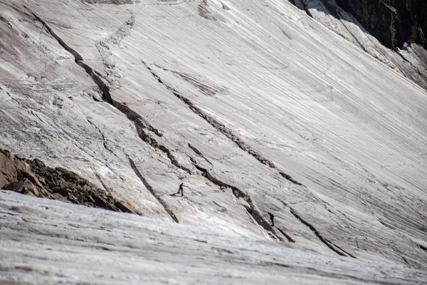 在多雪的山上徒步旅行的旅客在阳光充足的情况下经过岩石山脊 — 图库照片