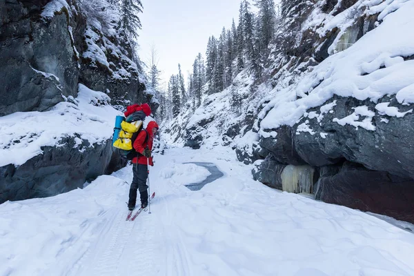 在阳光明媚的冬日 穿着保暖运动服背着背包在雪山徒步旅行 — 图库照片