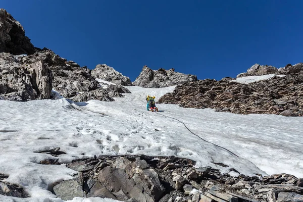 冬の晴れた日に雪の山の中でバックパックハイキングと暖かいスポーティ服で旅行者 — ストック写真
