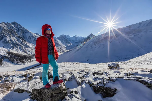 traveler in warm sporty clothes hiking in snowy mountains at sunny winter day