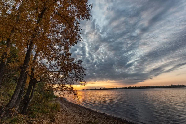 Autumn or summer sunset or sunrise on the river, a very beautiful sky, the sun comes out of the clouds