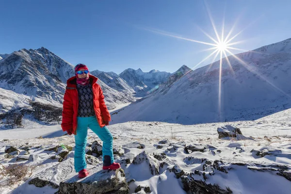 traveler in warm sporty clothes hiking in snowy mountains at sunny winter day