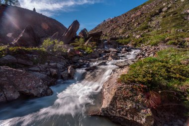 Güneşli baharda kayalık dağlarda akan hızlı dağ deresinin resimsel görüntüsü 