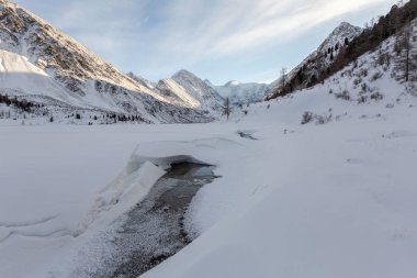 Soğuk dağ nehrinin güneşli kış günündeki manzarası. 
