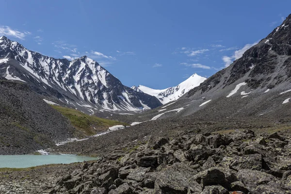 Mavi nehir manzarası ve Tien Shan dağlarının karlı tepeleri baharda güneşli bir günde. 