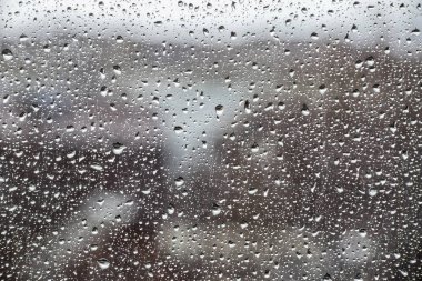 Bulanık doğal arkaplanda küçük yağmur damlaları olan cam, yakın görüş