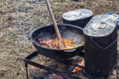 Kamp gezisinde yemek pişirmek. Kazan ateşte, içinde yahni var.
