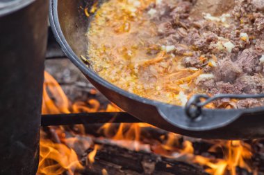 Kamp gezisinde yemek pişirmek. Kazan ateşte, içinde yahni var.