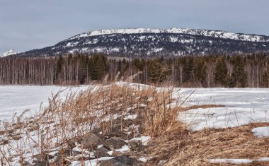 Dağlarda kış manzarası. Gökyüzünde bulutlar, güneşli bir gün. Bir sürü kar, buz, soğuk alan. Ural Dağları, Rusya.