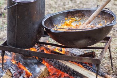 Kamp gezisinde yemek pişirmek. Kazan ateşte, içinde yahni var.