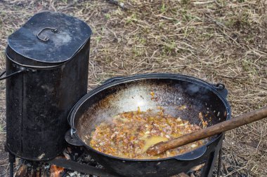 Kamp gezisinde yemek pişirmek. Kazan ateşte, içinde yahni var.