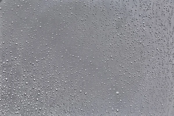 glass with small drops of rain on blurred natural background , close view