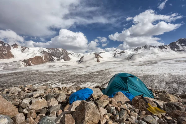 Mountain landscape with a tent. Mountains, glacier and sky with clouds. Summer in the mountains. Mountaineering