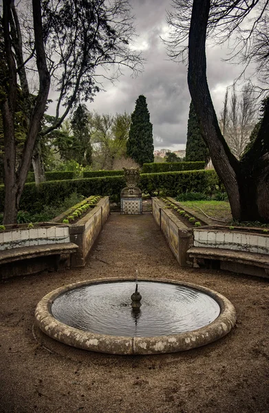 Small round fountain in a garden in winter day with overcast sky
