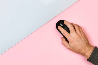 Pembe ve gri arka planda bilgisayar fareyi kullanan bir adam