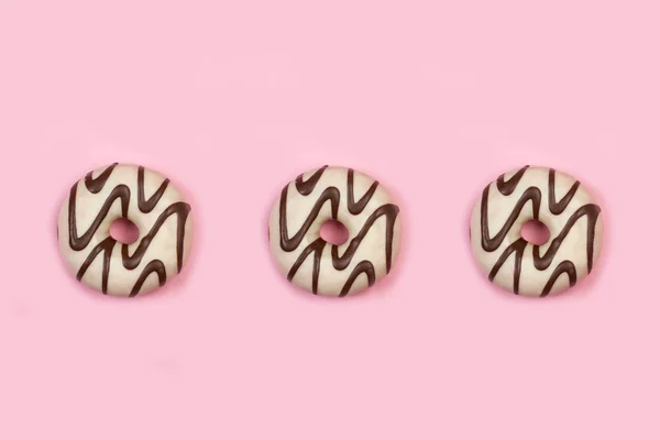 ピンクの背景に白と黒のチョコレートドーナツ — ストック写真