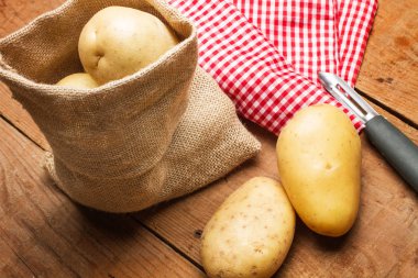 Patates ahşap bir masa üzerinde bir çuval bezi çanta