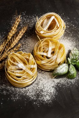 Karanlık bir arka planda fesleğen yaprakları ve un ile Ham yuva noodle