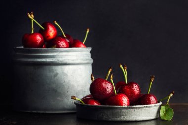 Siyah bir arka planda metal bir kavanozda ıslak kiraz