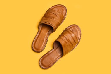 Sarı arka planda bir çift deri sandalet