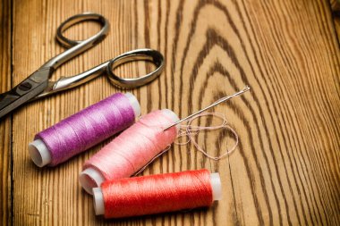 Ahşap bir masa üzerinde dikiş iplikleri havuzları ve makas