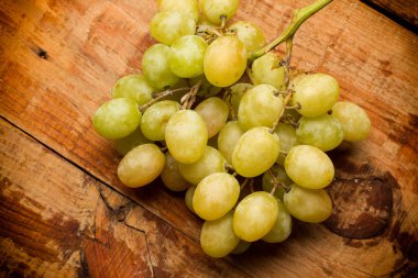 Tahta bir masada bir demet yeşil üzüm.