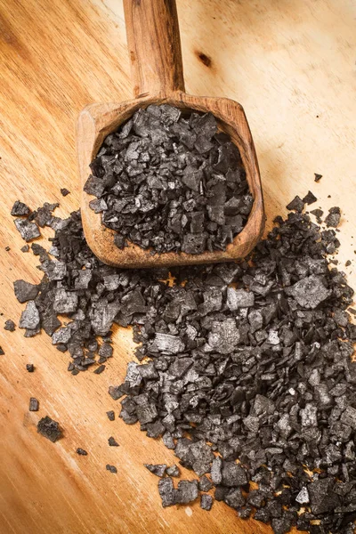 Black salt in flakes on a wooden spoon