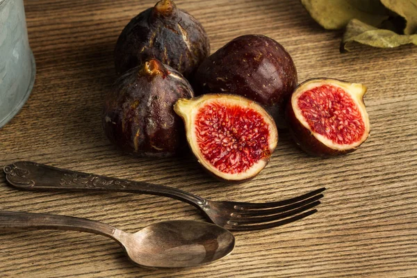 Çatal ve kaşıkla tahta bir masada incir ve iki yarım incir