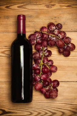 Kırmızı üzüm ve tahta bir masada bir şişe kırmızı şarap