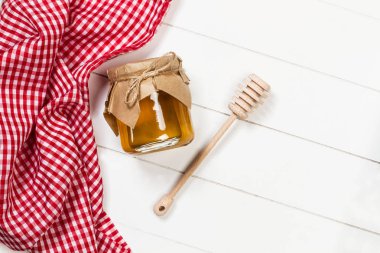 Beyaz ahşap bir masada bir kavanoz bal