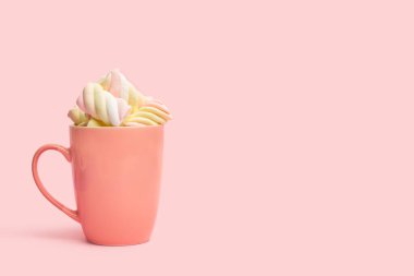 Pembe kupada sarı ve pembe şekerlemeler ve pembe bir arka plan. 