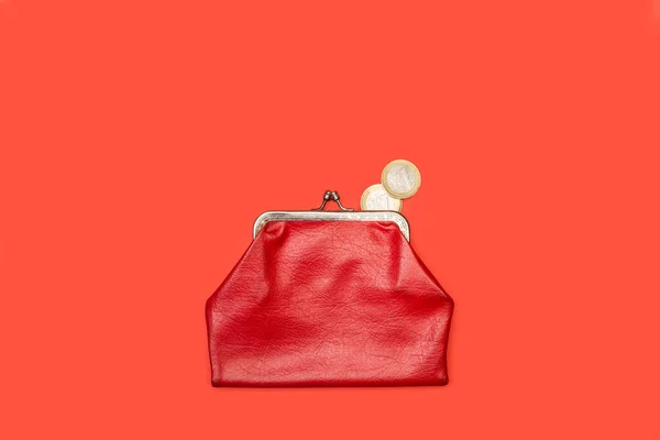 Old red coin purse with one euro coins on a red background