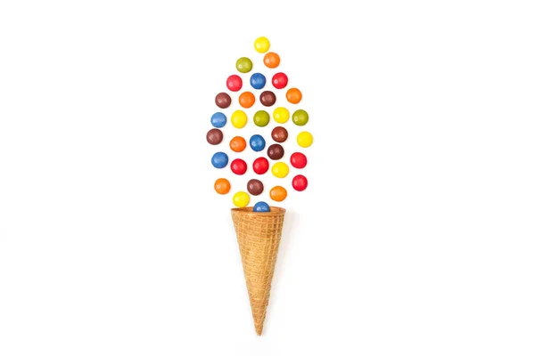 Multicolored hard shell chocolate candies and a wafer cone isolated on a white background