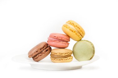 Beyaz bir tabakta ve beyaz bir arka planda izole edilmiş çok renkli makaronlar.