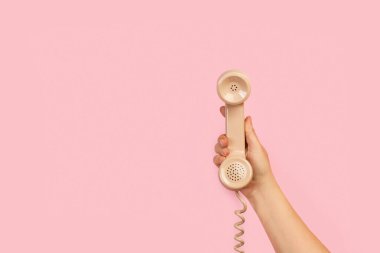 Kadınların el ele tutuştuğu pembe arka planda fotokopi alanı olan eski bir telefon.