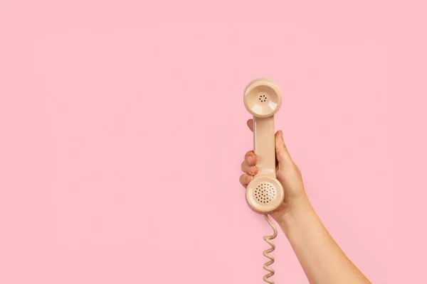Kadınların el ele tutuştuğu pembe arka planda fotokopi alanı olan eski bir telefon.