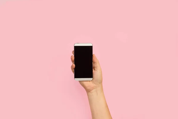 女用手拿着粉色背景的智能手机 — 图库照片