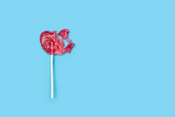 Kırık bir kırmızı kalp açık mavi arka planda lolipop şeklindeydi.
