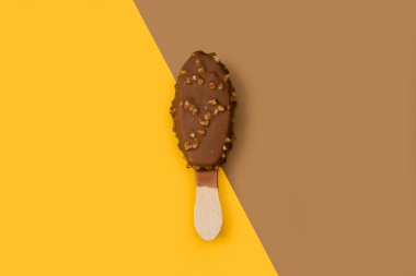 Kahverengi ve sarı arka planda fıstıklı buzlu lolipop.