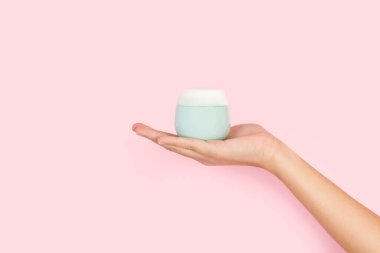 Pembe arka planda nemlendirici krem tutan kadının elinde fotokopi alanı var.