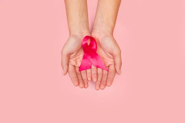 Woman hands holding a pink bow in a top view